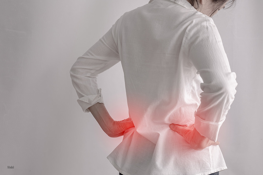 woman holding her hip in pain while running on a track field.