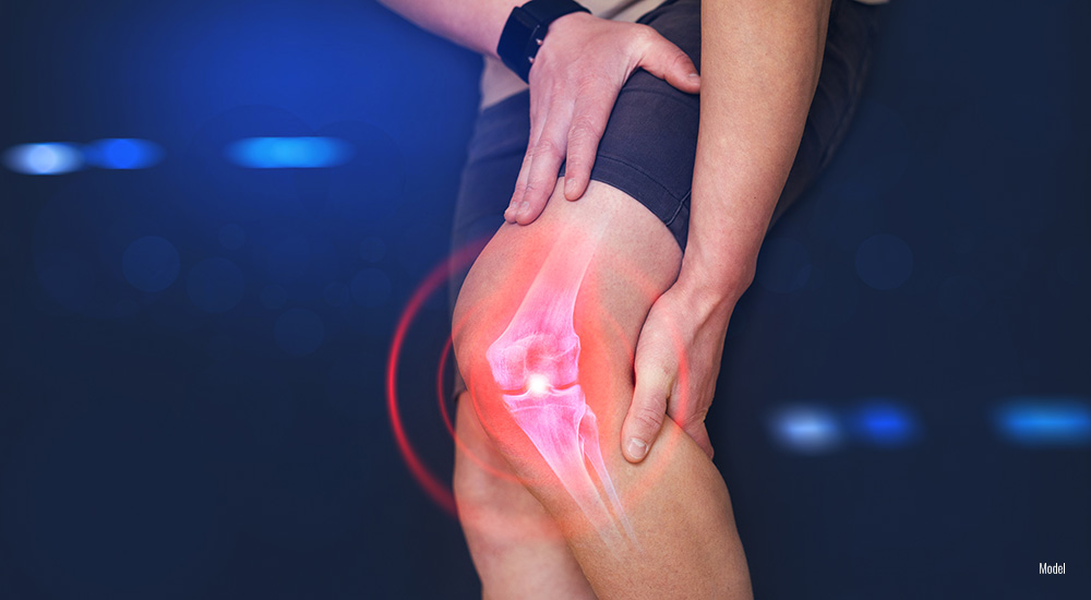 close up of person's knee as they hold it in pain.